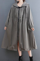 Oversized all-weather water-resistant windbreaker in neutral color with drawstring waist and elastic cuffs, styled with ankle boots