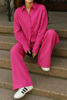 Woman wearing vibrant raspberry red 100 cotton Wanderlust two-piece set with relaxed fit sitting on steps