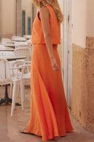 Woman wearing orange cotton-linen blend sleeveless vest and flowing skirt two-piece set outdoors
