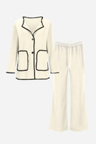 Cream knit cardigan and pants set with black contrast trim and pockets, soft comfortable fabric design.