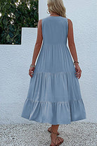 Back view of a woman wearing a light blue Bohemian tiered midi dress with a flowing, sleeveless design.