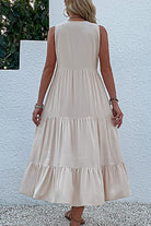 Back view of a sleeveless Bohemian tiered midi dress in a light beige color with flowing tiers and empire waist design.