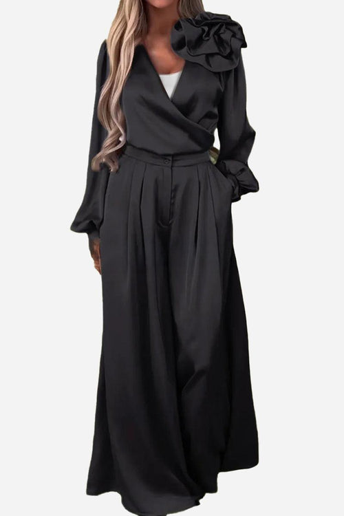 Black satin two-piece set with statement shoulder blouse and flowing palazzo pants, elegant and luxurious for special occasions.