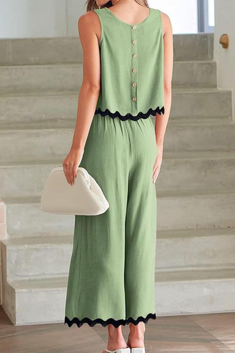 Back view of woman wearing green scalloped trim sleeveless top and wide leg pants set with button details and black scalloped edges.