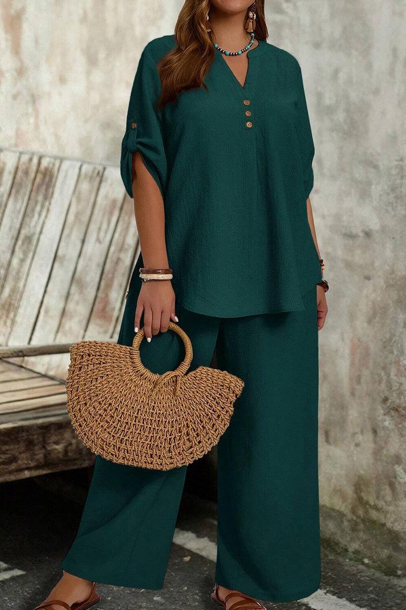 Woman wearing wrinkle-free wide leg pants and button-front top set with roll-tab sleeves, holding a woven straw handbag.