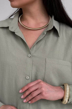 Close-up of woman wearing relaxed fit wide-leg two-piece set in light green with gold necklace and bracelet