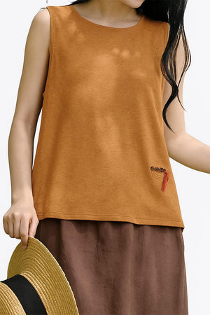 Woman wearing Dandelion Fields Cotton Linen sleeveless top in brown with embroidered detail, paired with matching skirt and holding a straw hat.