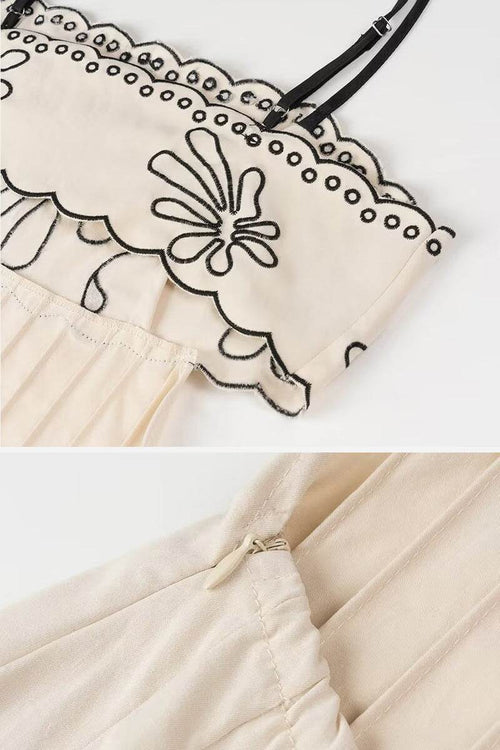 Close-up of artisan embroidered scalloped neckline and waist detail on bohemian romance dress with black floral stitching on cream fabric