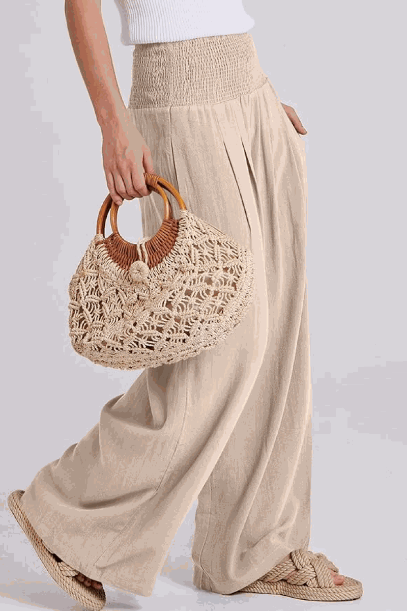 Woman wearing oversized linen blend palazzo pants and holding a woven handbag, part of the Oversized Linen Leaved-IN Set.