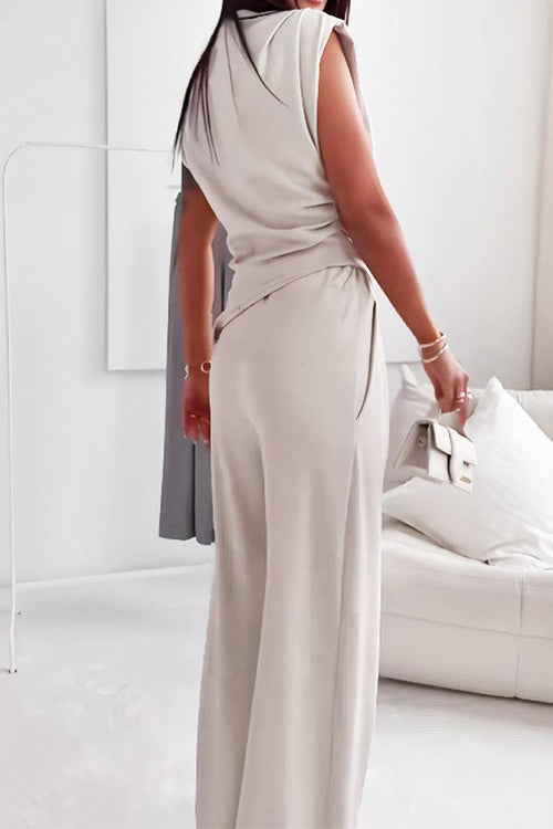 Woman wearing Manhattan Lines Draped two-piece set with asymmetrical sleeveless top and wide-leg pants in beige.