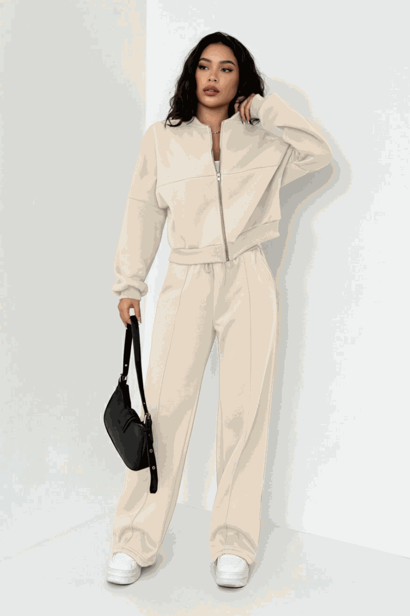 The Voyager Zip Set beige zip-front sweatshirt and wide-leg joggers on model with black handbag and white sneakers