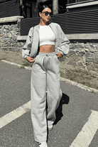 Woman wearing The Voyager Zip Set light gray zip-front sweatshirt and wide-leg joggers with pockets outdoors