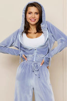 Woman wearing light blue velour tracksuit with cropped hoodie and high-waist drawstring pants