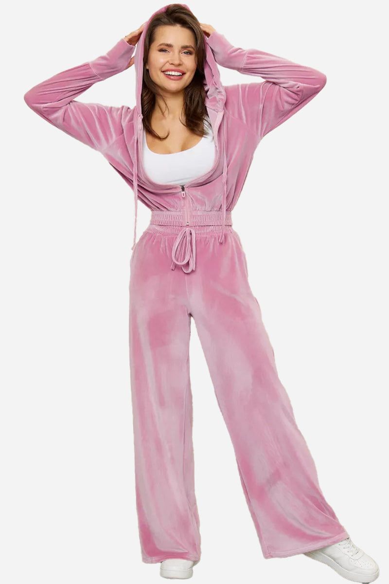 Pink velour tracksuit with cropped hoodie and high-waist pants on smiling woman