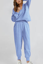 Woman wearing light blue unisex half-zip pullover and sweatpants set in casual pose