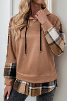 Woman wearing a cozy brown Countryside Layered Hoodie with plaid accents on sleeves and hem, styled with gray pants.