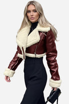 woman wearing cropped faux leather sherpa jacket with cream trim and black pants