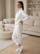 Woman wearing a white Warm & Easy Two-Piece Set with a pullover hoodie and matching pants in a cozy living room setting