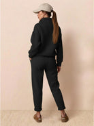 Woman wearing black Warm & Easy Two-Piece Set with relaxed fit, pullover hoodie, and matching pants against beige background