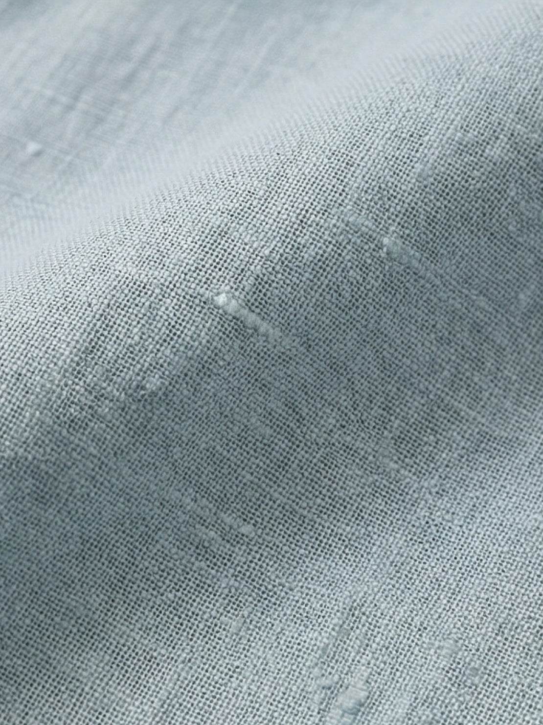 white Tencel-linen pleated wide-leg pants with structured waist closure and floor-skimming silhouette