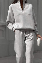 woman wearing cotton-blended two-piece tracksuit with high collar and zippered jacket in monochrome solid color