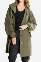 Water resistant oversized windbreaker jacket in olive green with hood and elastic cuffs worn by a woman