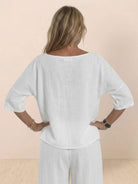 Back view of a woman wearing a white short-sleeved pullover and wide trouser matching set made of lightweight breathable cotton fabric.
