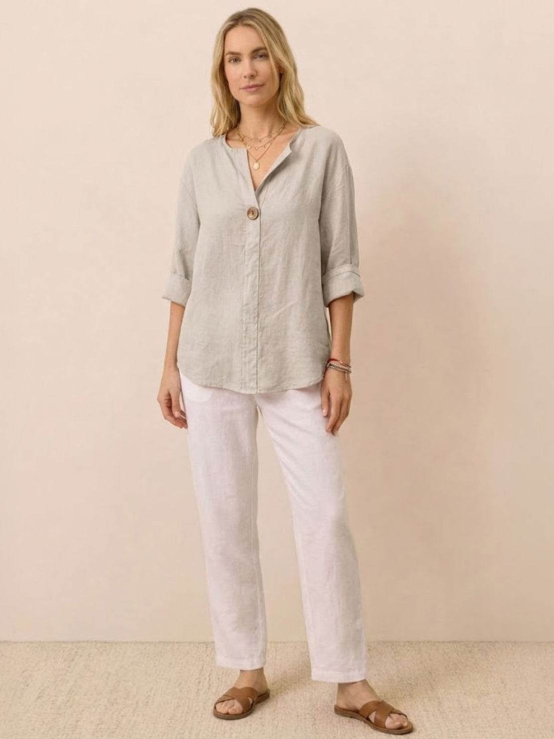 Woman wearing a pure linen age-defying button detail shirt and white pants, styled for comfort and elegance