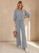 woman wearing round neck loose fit cozy two-piece set in gray with wide-leg pants and long sleeves, holding a brown handbag