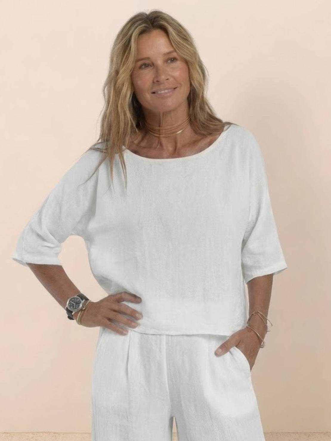 Woman wearing white short-sleeved pullover and wide trouser matching set in breathable cotton fabric with relaxed fit and deep pockets.