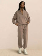 Woman wearing a cotton-blended two-piece tracksuit with high collar and deep zipper, styled for casual confidence and comfort