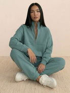 Woman wearing a cotton-blended two-piece tracksuit with high collar and zipper, styled for casual athleisure look