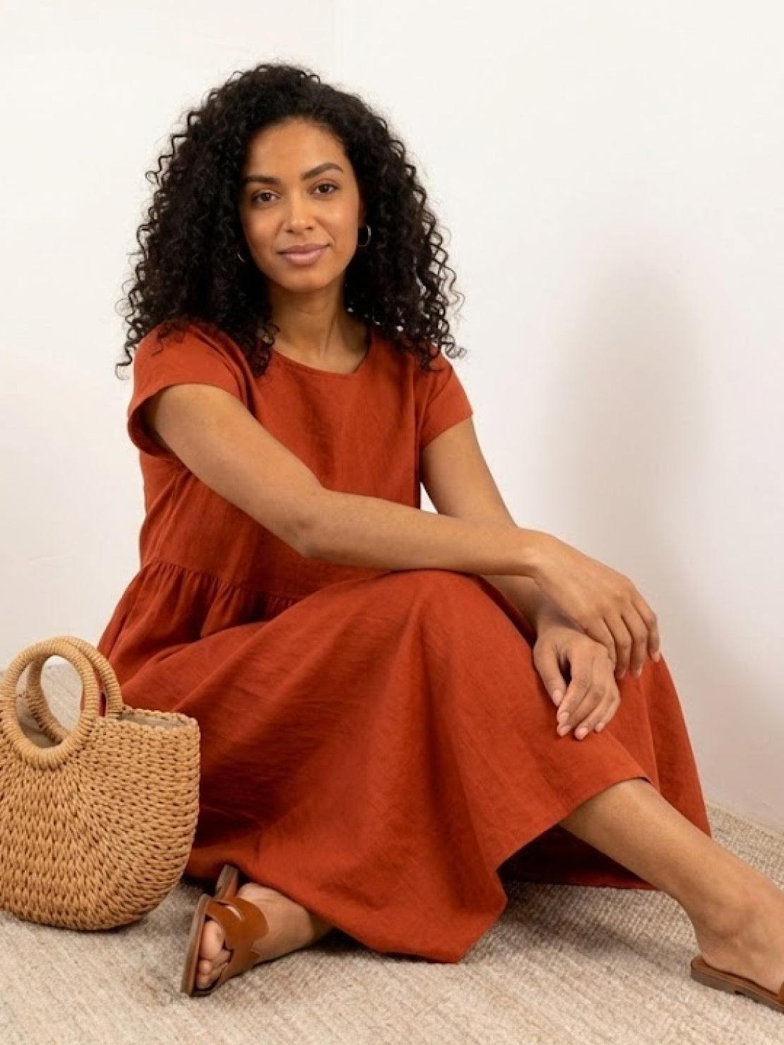 Woman wearing capped-sleeve voluminous pleated midi dress with flowing skirt and gathered waist