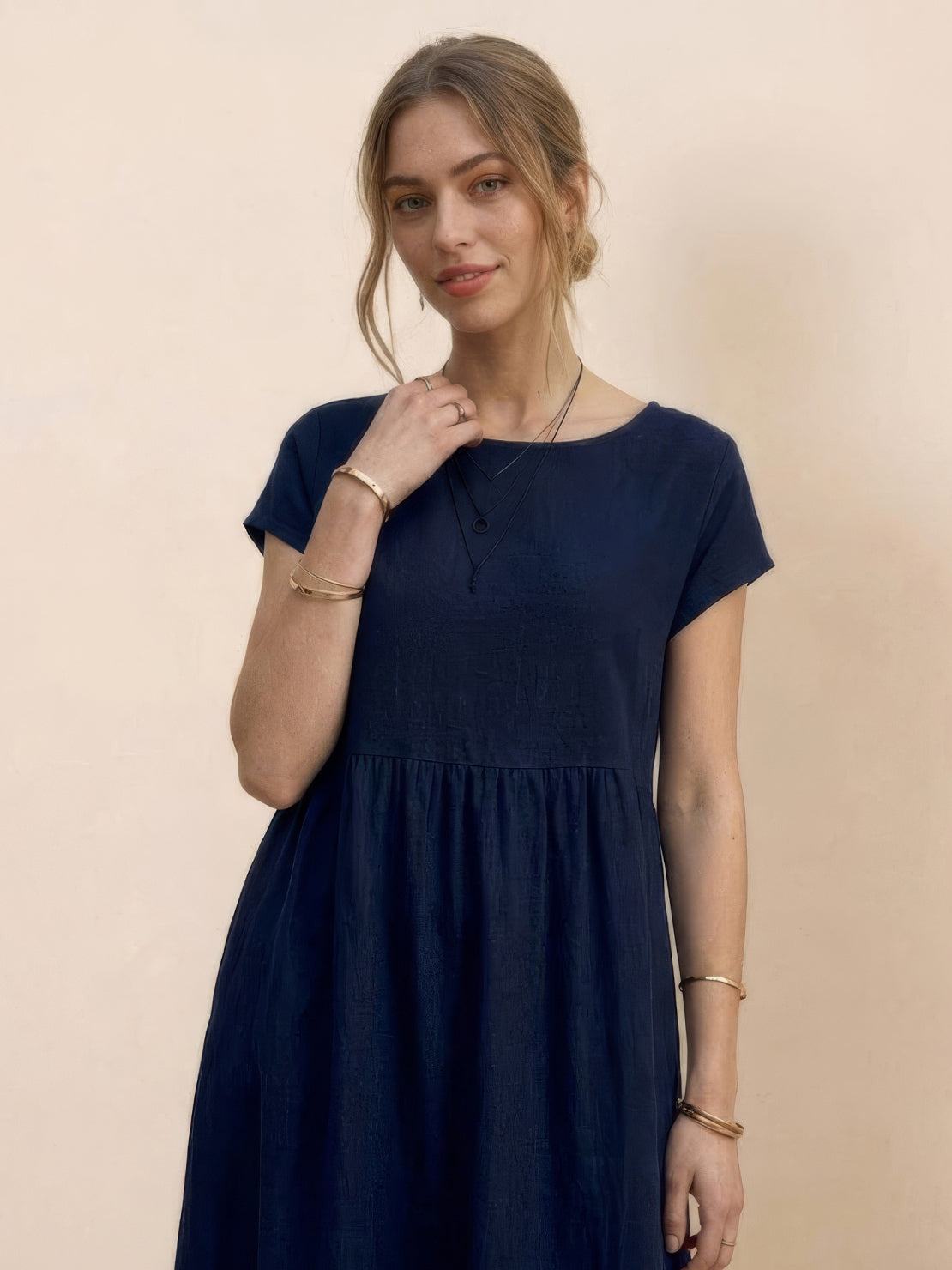 Woman wearing capped-sleeve voluminous pleated midi dress with pockets and flowing skirt