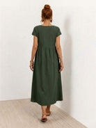 Woman wearing a capped-sleeve voluminous pleated midi dress with flowing skirt and pockets