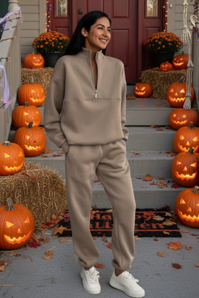 Woman wearing beige Classic Airplane Set tracksuit standing among Halloween pumpkins on front porch
