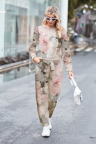 Woman wearing a relaxed cotton-linen monochrome floral print longline top and wide-leg pants set walking outdoors with white sneakers and handbag.