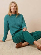 Woman wearing a teal knit sweater and relaxed trousers embodying European minimalism style
