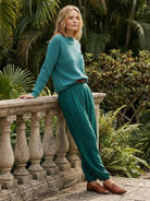 European Minimalism relaxed knit sweater and drapey trousers in teal with casual loafers outdoors