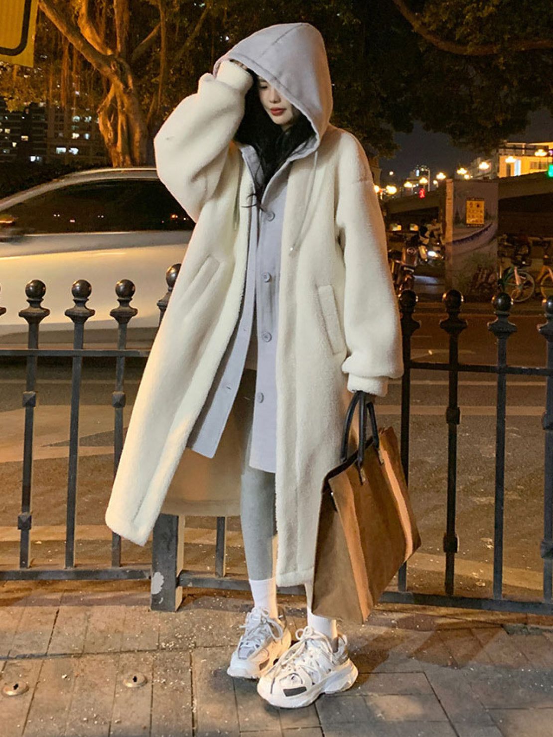 Woman wearing an oversized cozy sherpa-lined long coat with a hood, styled for everyday casual wear at night.