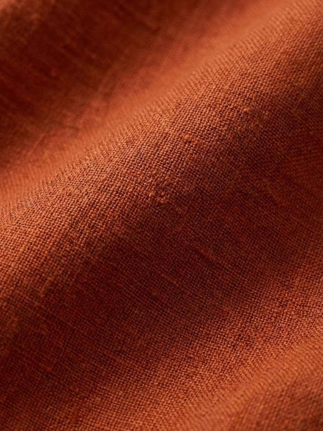 close-up of textured rust-colored linen fabric for loose solid color two-piece set