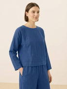 Woman wearing loose solid color two-piece set in blue with long sleeves and wide-leg pants