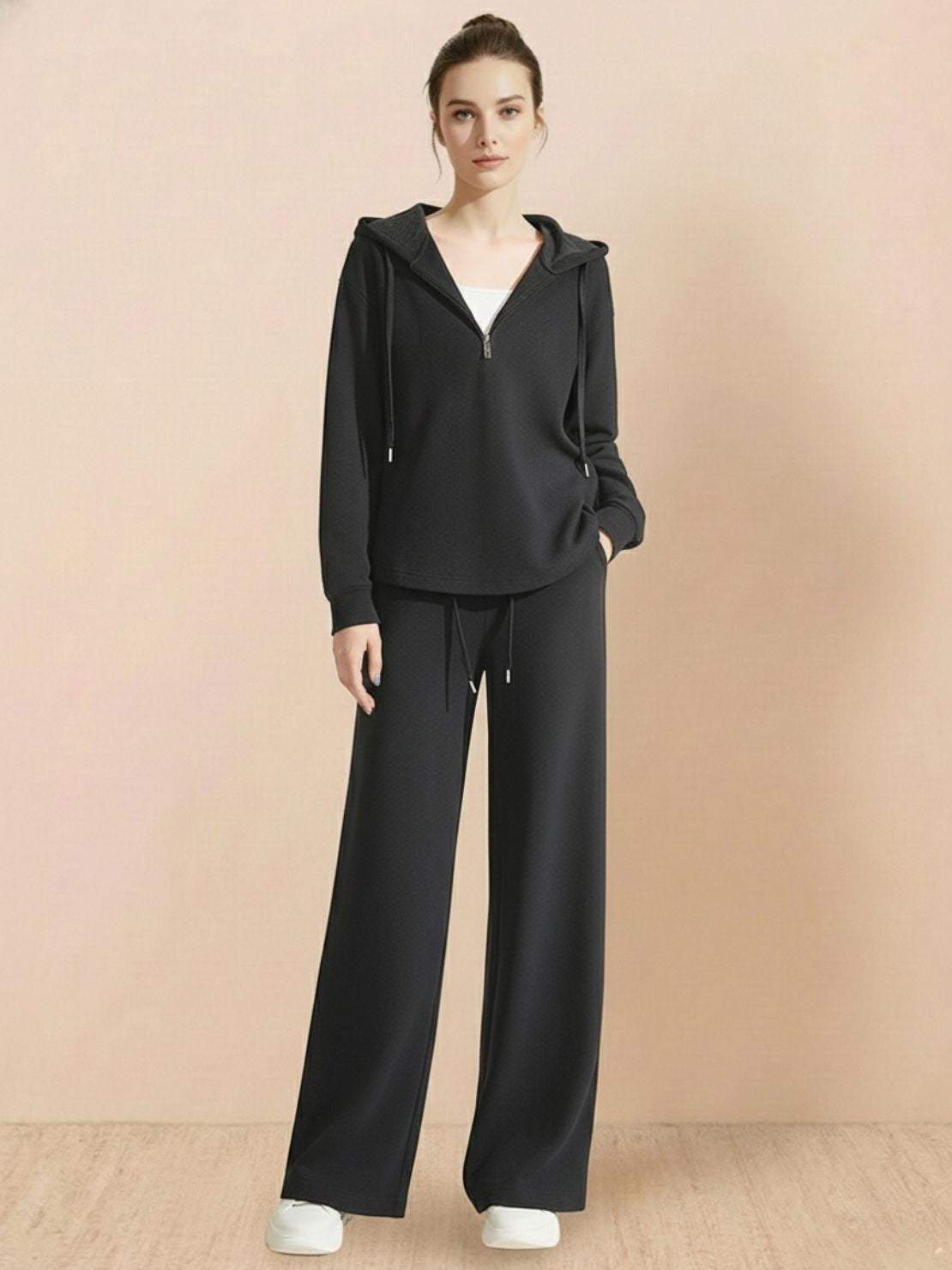 Woman wearing black Lyocell-Blend Hooded Set with wide-leg pants and hooded top against beige background