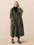 Oversized olive green waterproof windbreaker jacket with hood and large front pockets worn by woman