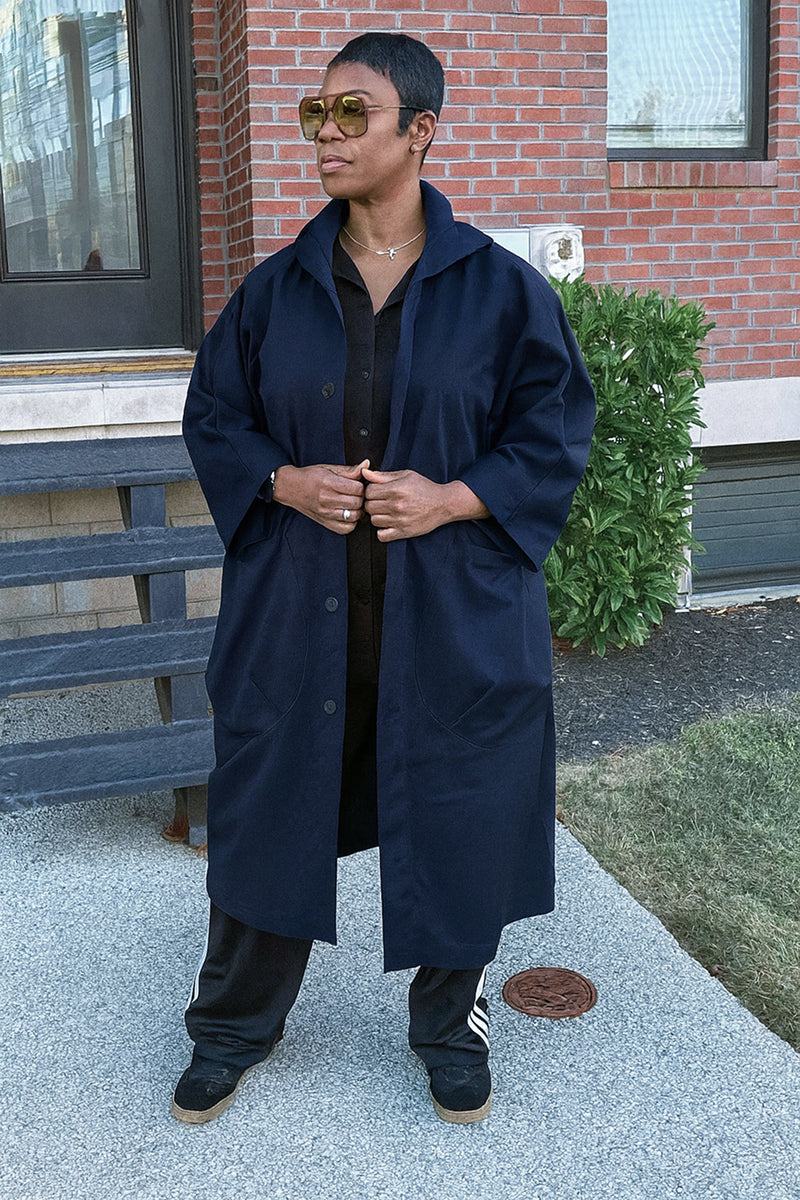 One size navy oversized water resistant windbreaker jacket with large pockets and snap-button closure worn outdoors