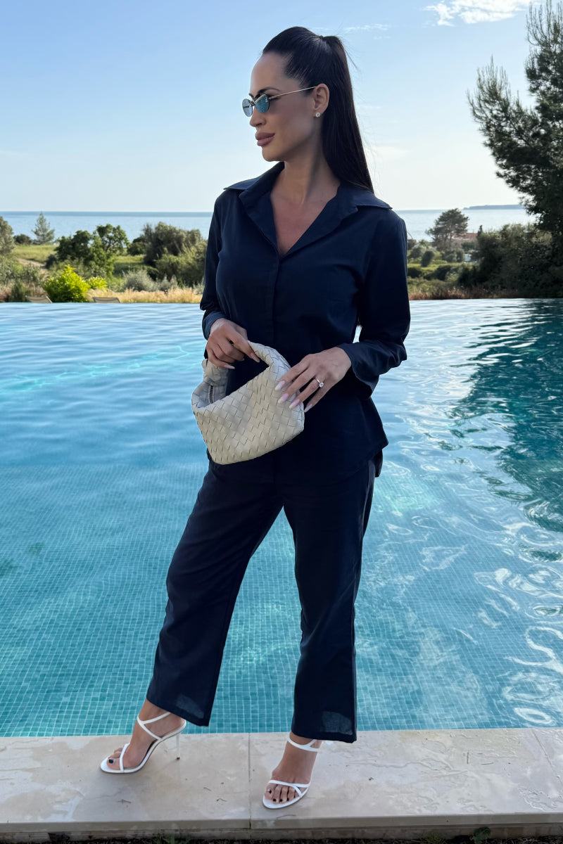 Woman wearing oversized 100% cotton black shirt and wide-leg pants co-ord set by poolside