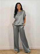 Woman wearing Silken Escape satin two-piece set with flowy wide-leg pants and fitted top