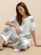 Woman wearing loose fit co-ord set with wide-leg floral print trousers and short-sleeve top in light linen-cotton fabric.
