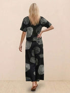 Woman wearing a black loose fit co-ord set with grey abstract floral prints, featuring a relaxed short-sleeve top and wide-leg trousers.