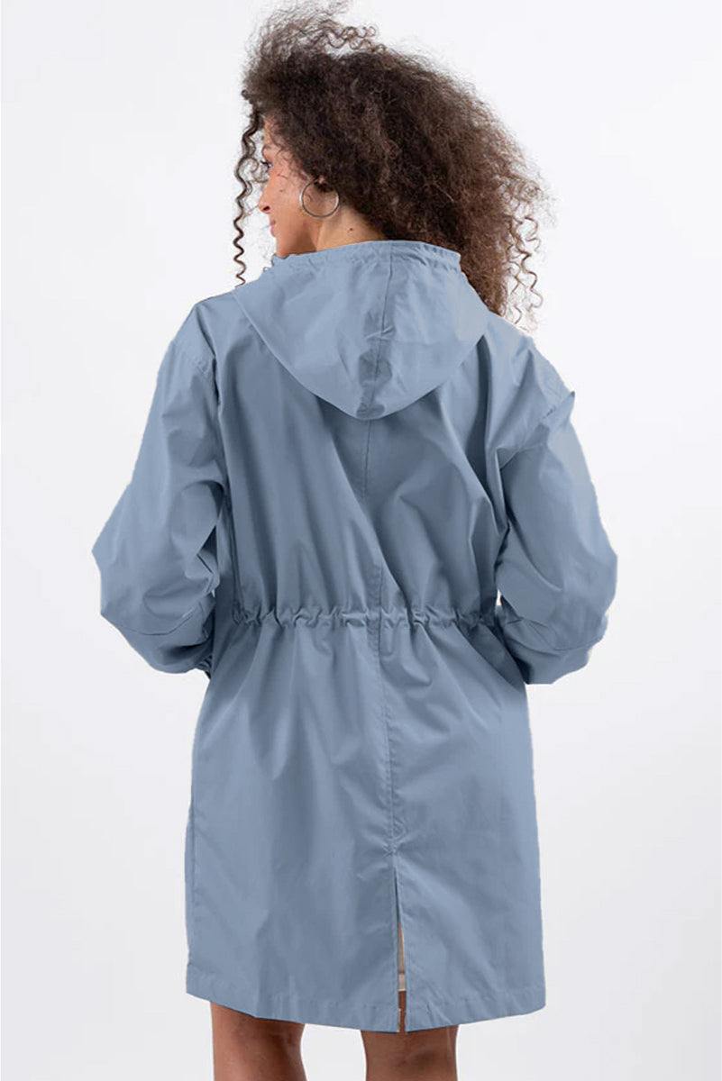 Back view of woman wearing oversized light blue Rain Couture Windbreaker with hood and adjustable waist